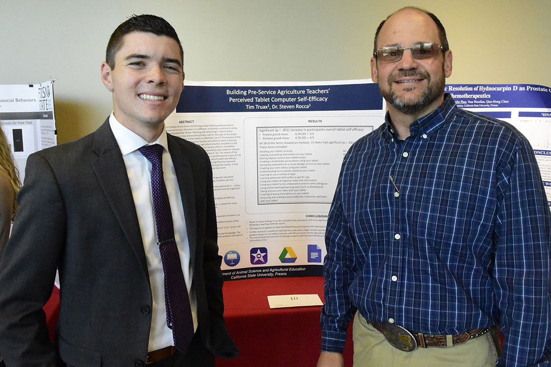 Tim Truax and Steve Rocca posing in front of a presentation board at the student research symposium