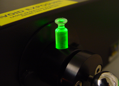 Close-up of vial, with juice illuminated by laser light.
