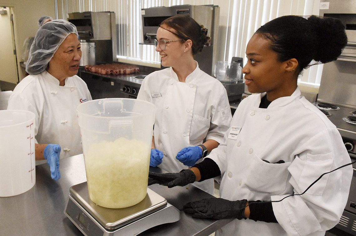 Diymond Walker prepares a meal in campus ktichen with instructor Harriet Tom and student Lindsey Jones.