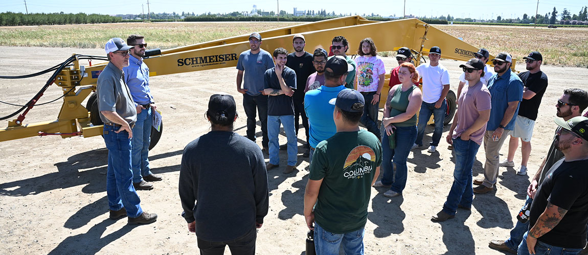 Andrew and Cory Cummings discuss the attributes of a new tri-plane land leveler their company (Schmeiser) donated to the campsu farm to a mech ag class.