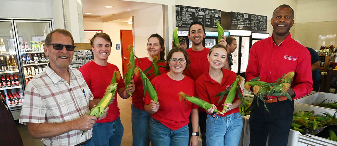 Dean Rolston S. Hilair,e farm manager Vincent Roos and students at the Gibson Farm Market on sweet corn sales opening day, 2024