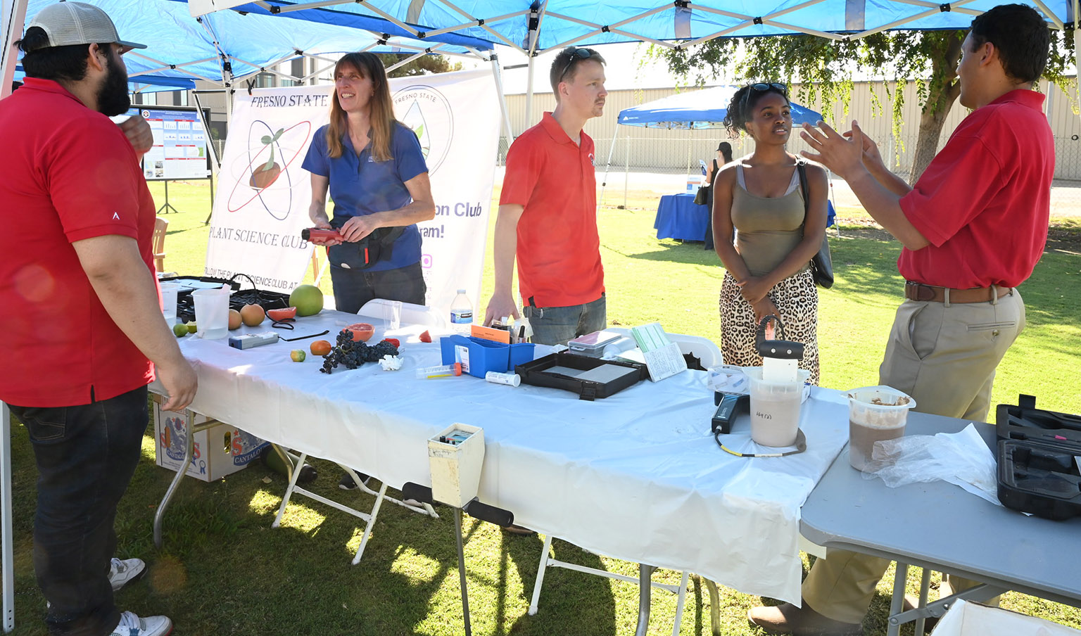 Student at irrigation club information table offers advice to youth at soil activity.