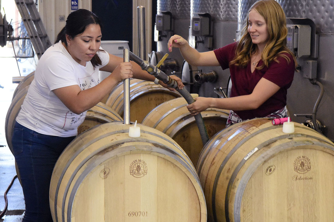 Karley Curtis and Monica Gutierrez working with wine barrels.
